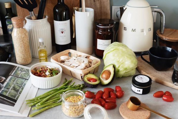 Assorted healthy food and vegetables set locating on gray countertop next to various utensils and appliances during cooking in stylish kitchen