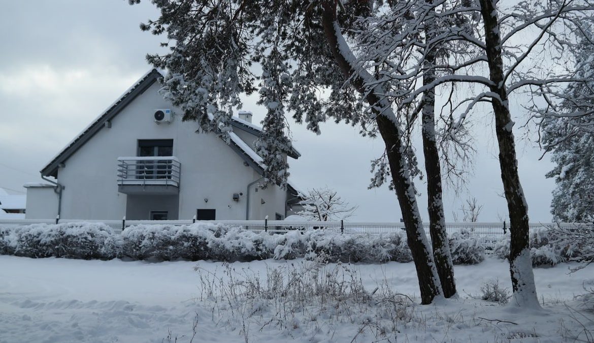 Beautiful snow-covered house surrounded by winter trees creating a peaceful scene.