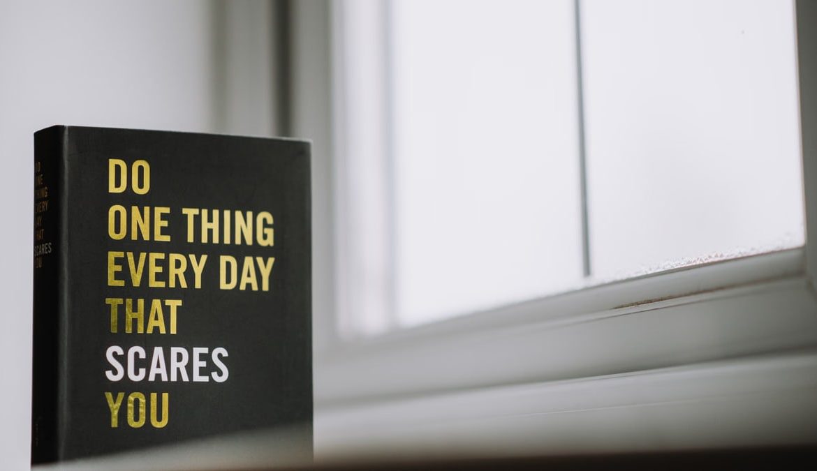 Rectangular shaped book with printed title on black hardcover on windowsill in house in daytime