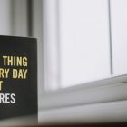 Rectangular shaped book with printed title on black hardcover on windowsill in house in daytime