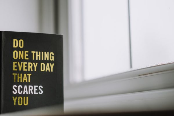 Rectangular shaped book with printed title on black hardcover on windowsill in house in daytime