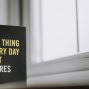 Rectangular shaped book with printed title on black hardcover on windowsill in house in daytime